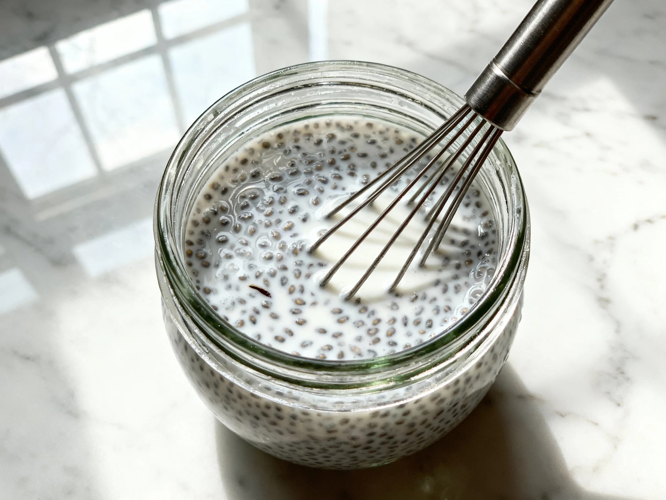 Food photography, Close-up of base chia pudding being stirred after 10 minutes in a glass jar: glossy, evenly gelling ch
