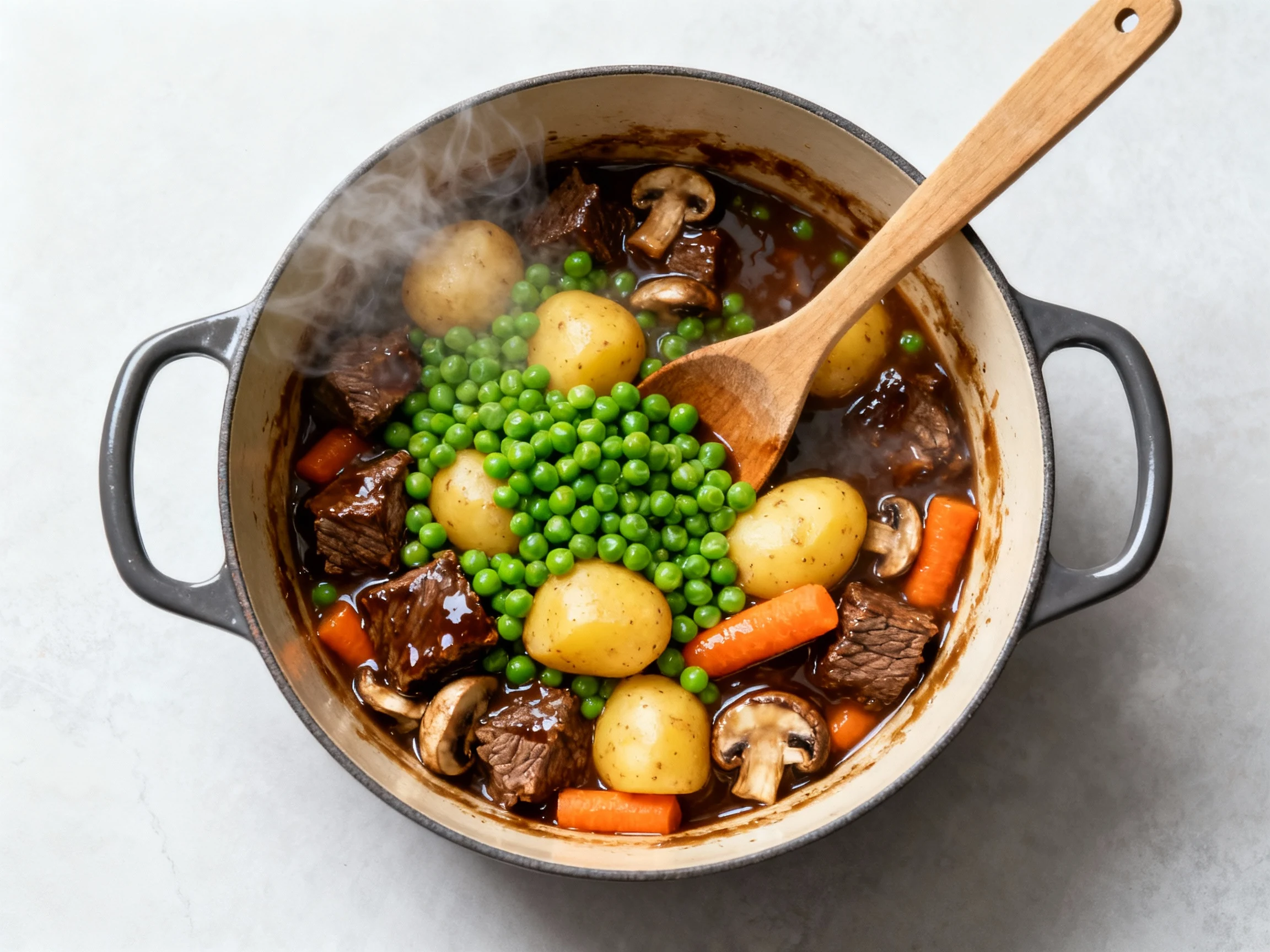 Food photography, Cooking process, overhead: Dutch oven mid-finish with bright green peas just stirred in, golden potato
