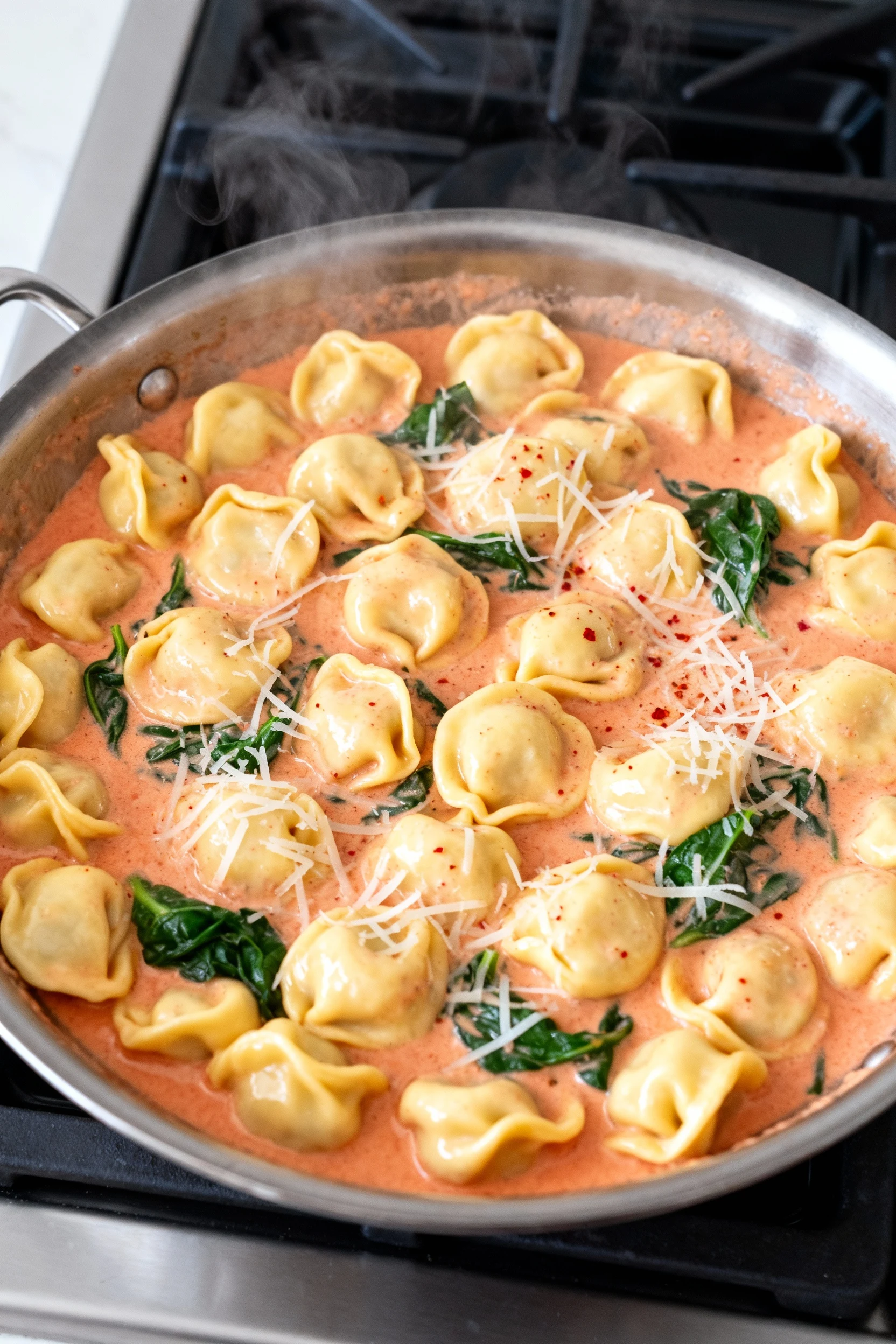 Food photography, Overhead shot of a wide skillet of cheese tortellini gently tossed in a velvety rosy tomato-cream sauc
