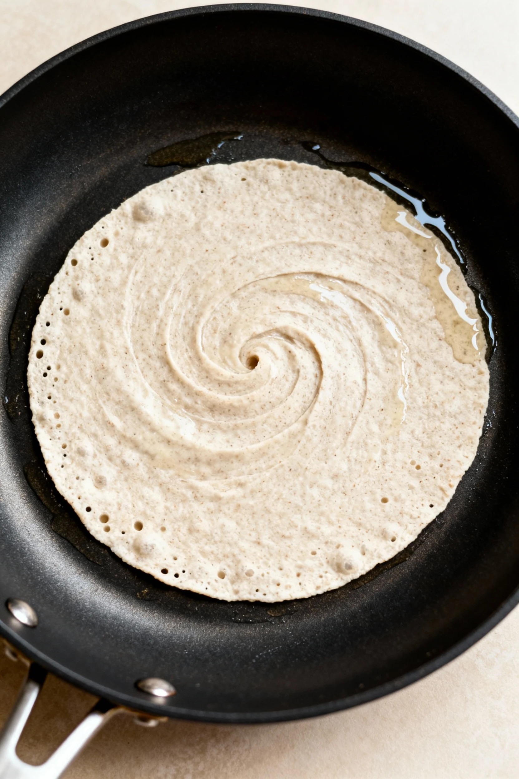 Food photography, Close overhead shot of a nonstick skillet on medium-low heat as thin, pourable coconut flour tortilla 