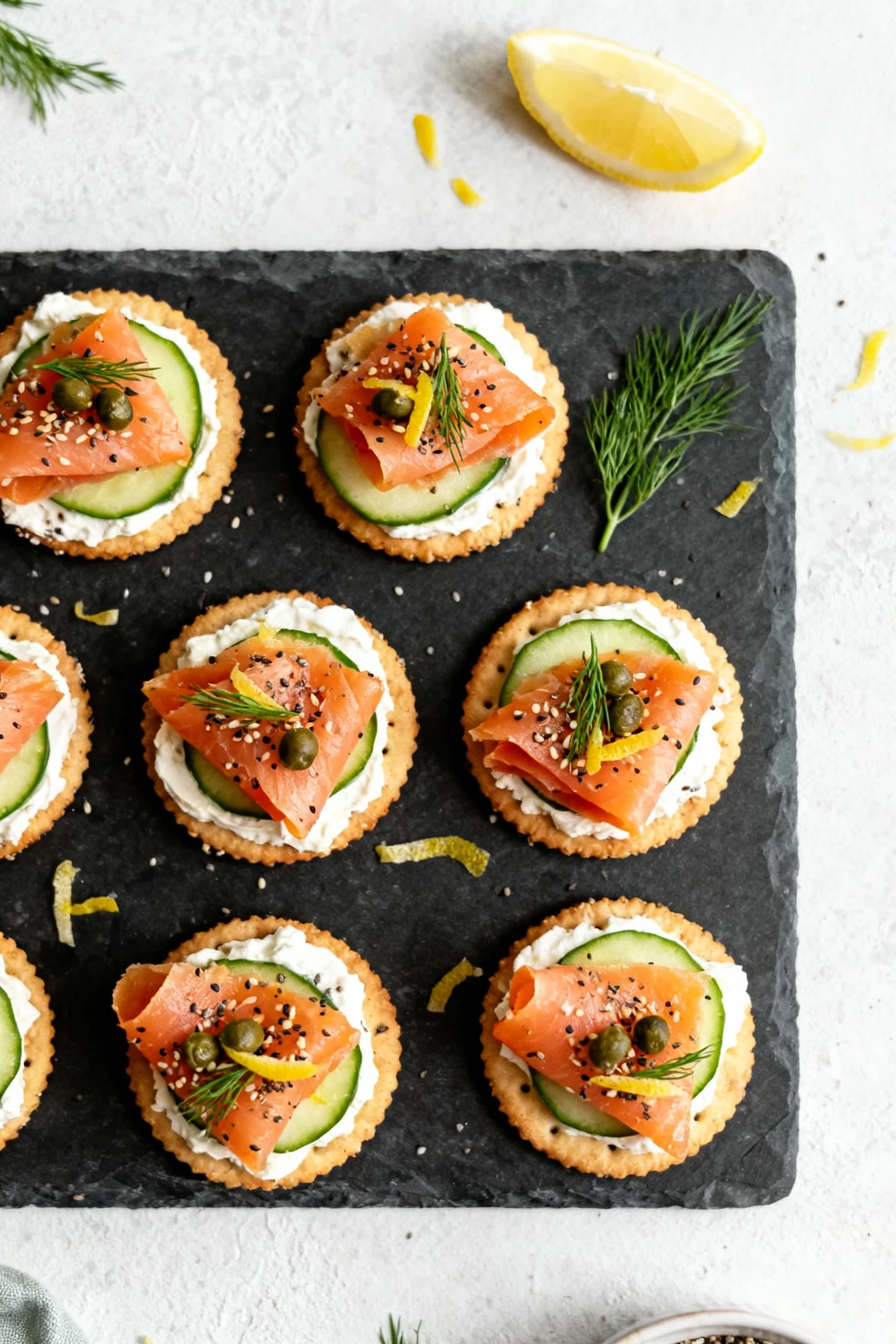 Overhead shot of Everything Bagel Smoked Salmon Bites on Ritz crackers: whipped cream cheese base, cucumber slice, folde