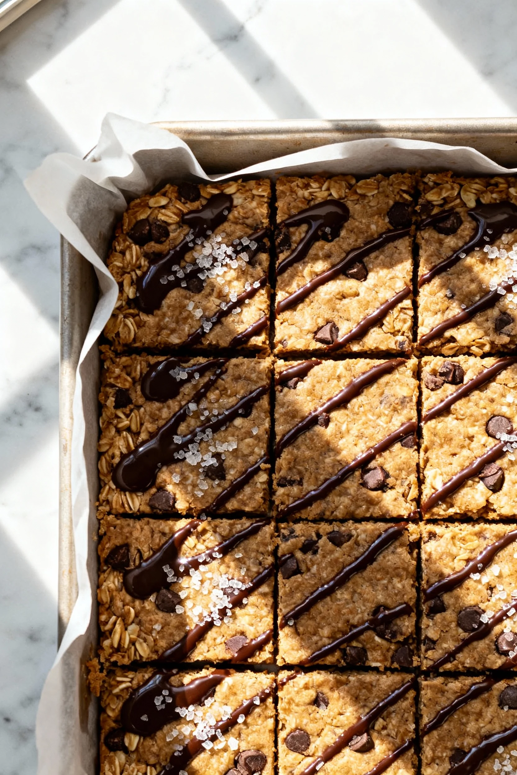 Overhead shot of classic no-bake chocolate chip oat bars pressed in an 8-inch parchment-lined pan, sliced into neat rect