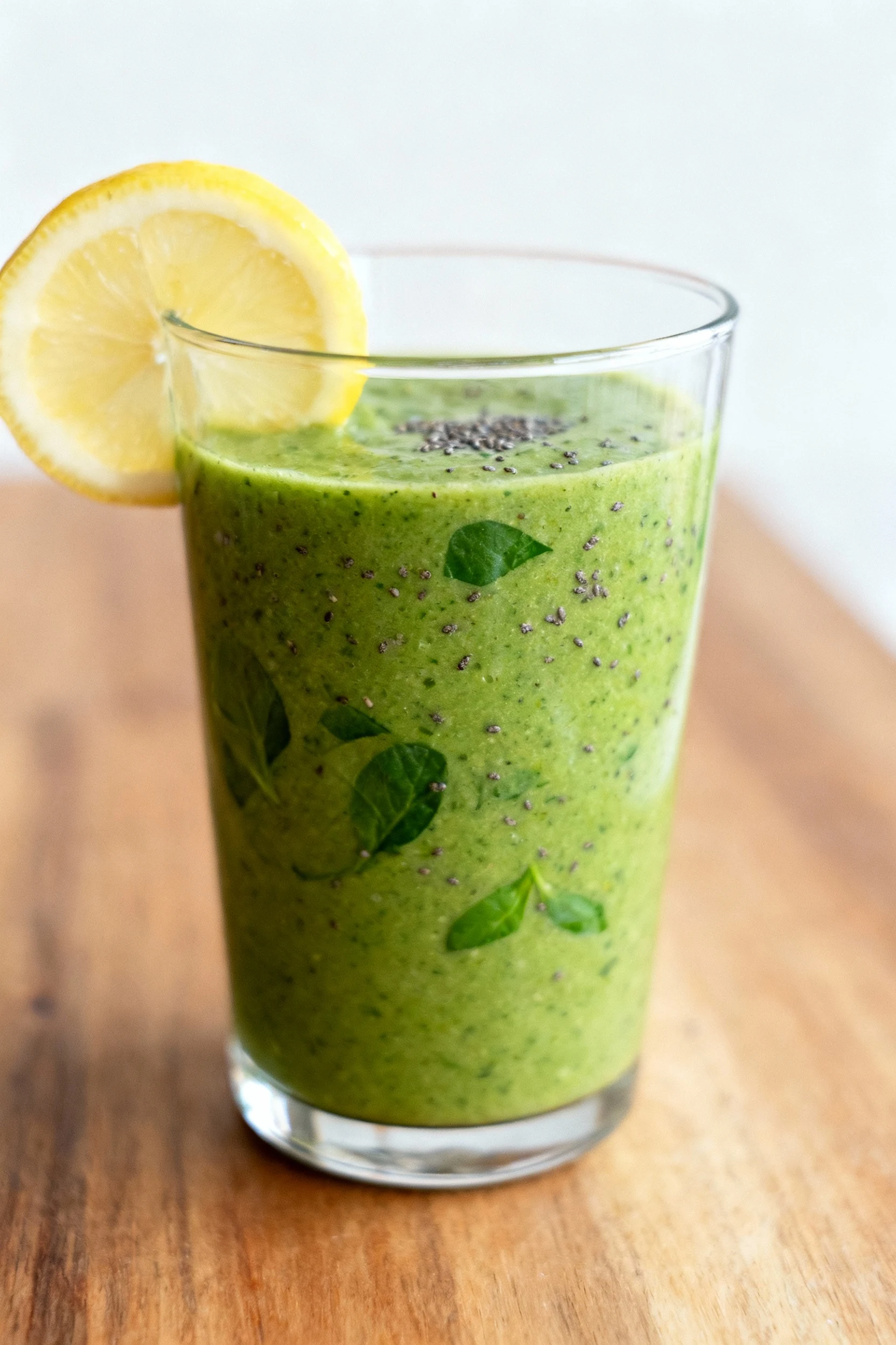 Close-up of the Green Power Fuel smoothie in a clear glass, vibrant green hue with flecks of spinach and chia seeds visi