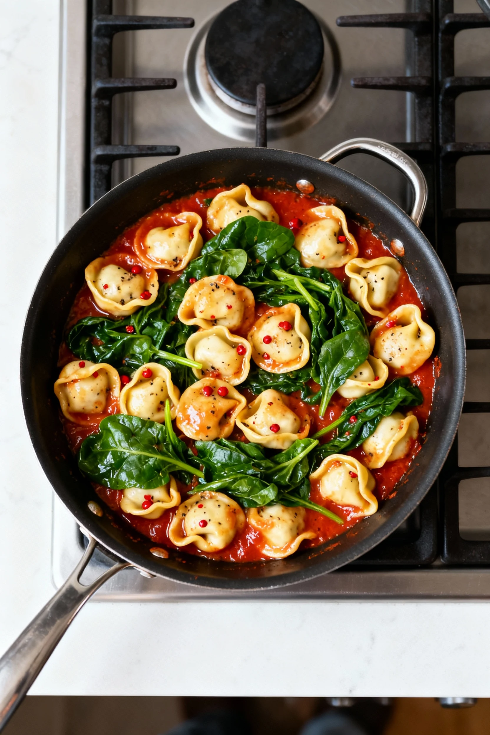 Food photography, 2. Overhead shot of sausage spinach tortellini simmering: plump cheese tortellini in glossy tomato sau
