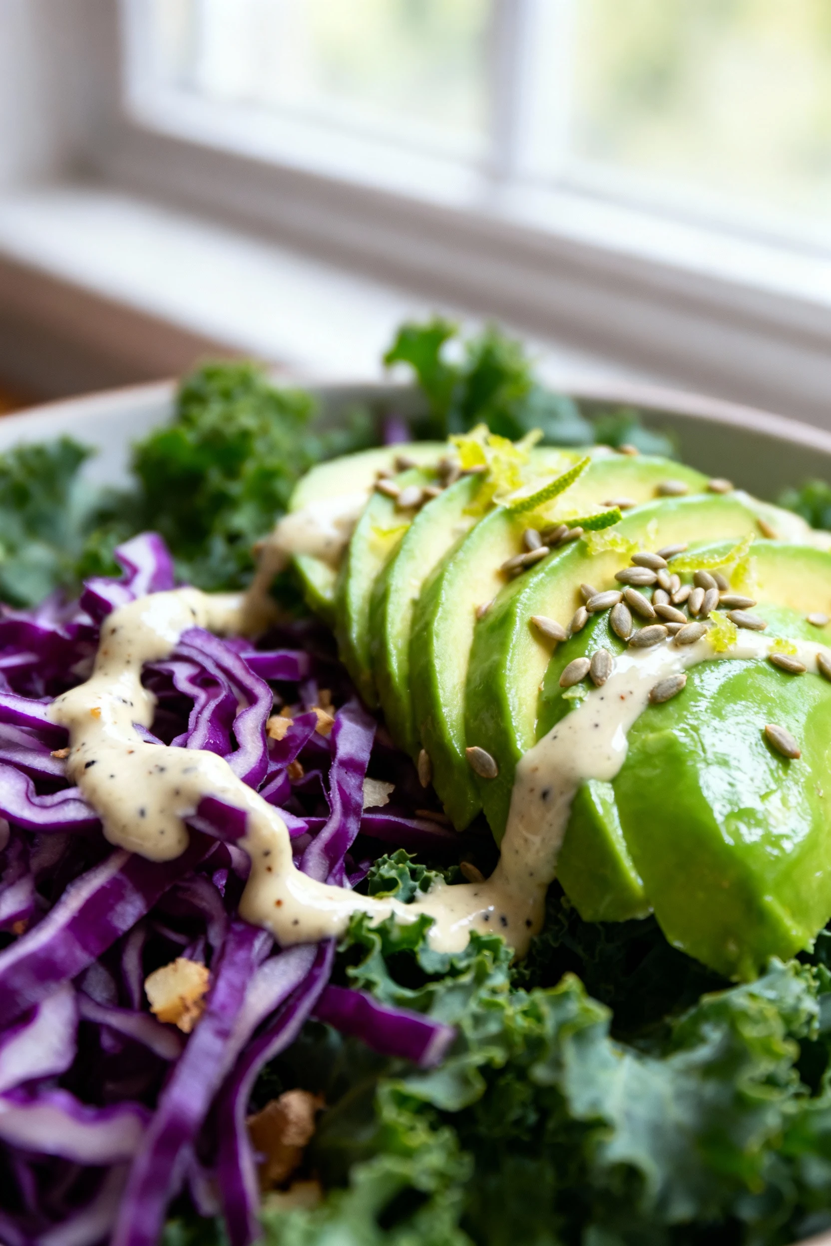 Macro close-up of creamy tahini–lime dressing clinging to shredded purple cabbage and softened kale, ginger and pepper f