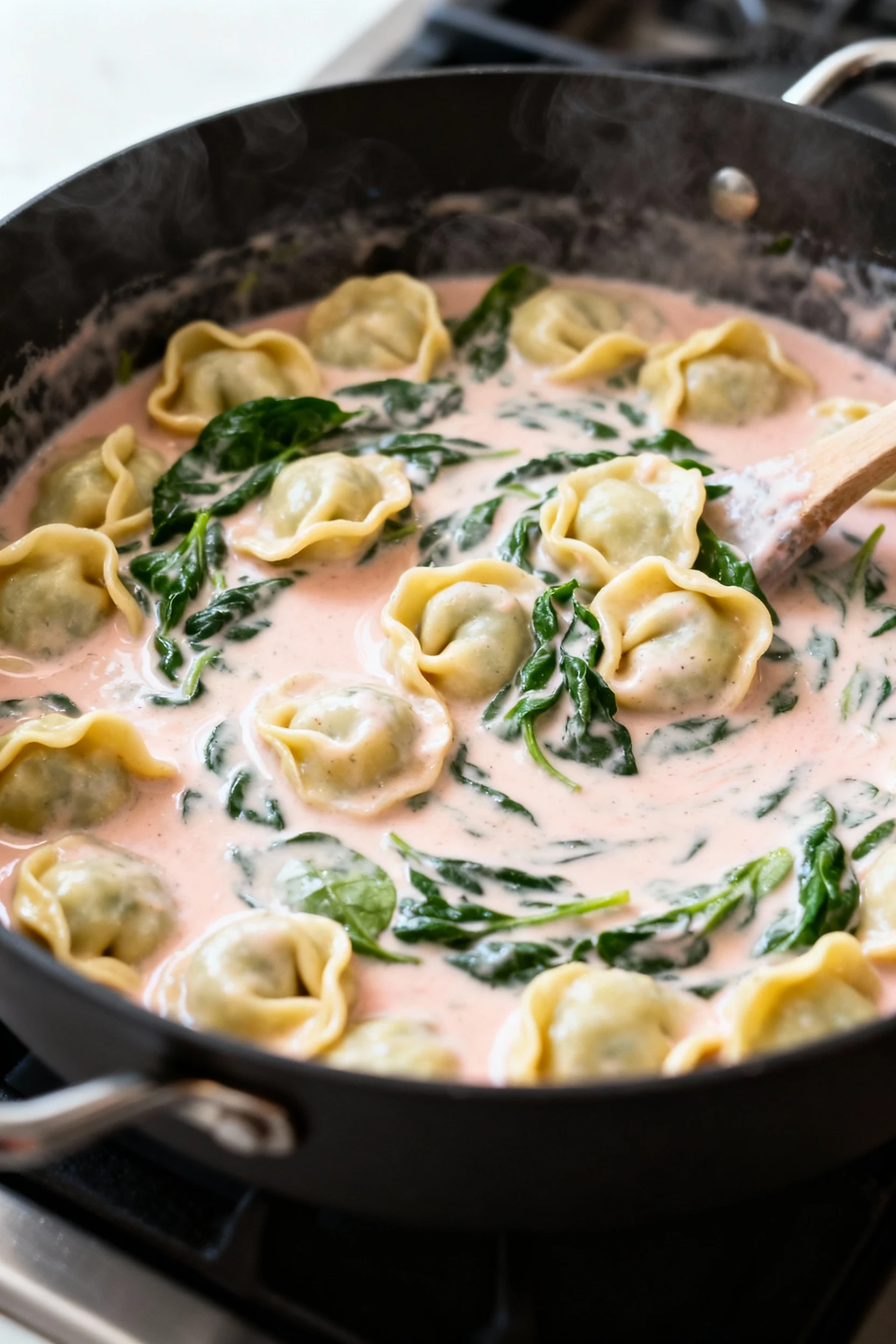 Food photography, 3. Cooking process: cream and spinach just stirred in, sauce turning silky and blush, tortellini nestl