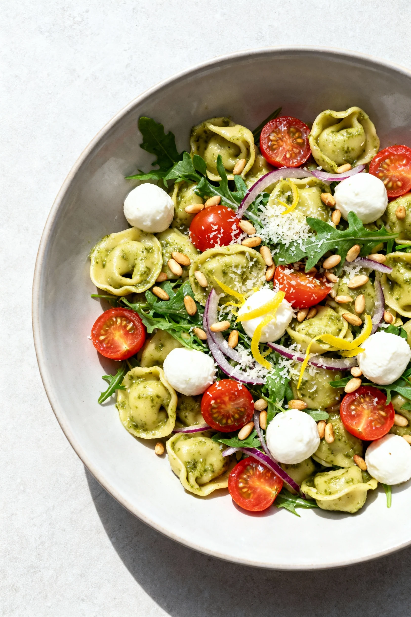 Food photography, Tasty top view: Overhead shot of the finished pesto tortellini pasta salad in a wide shallow bowl—al d
