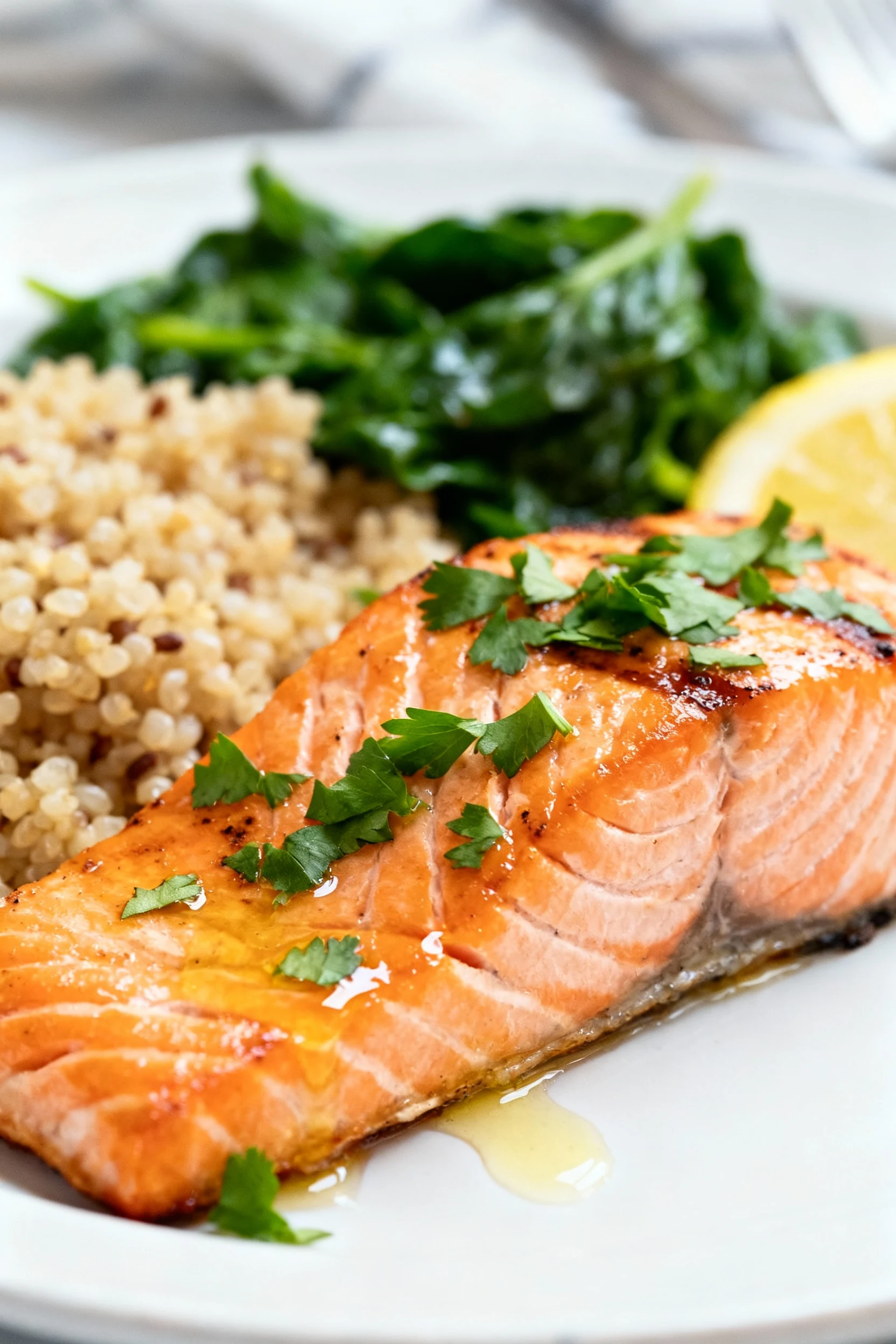 Close-up of grilled salmon fillet topped with fresh chopped parsley and a drizzle of lemon juice, flaky texture glisteni