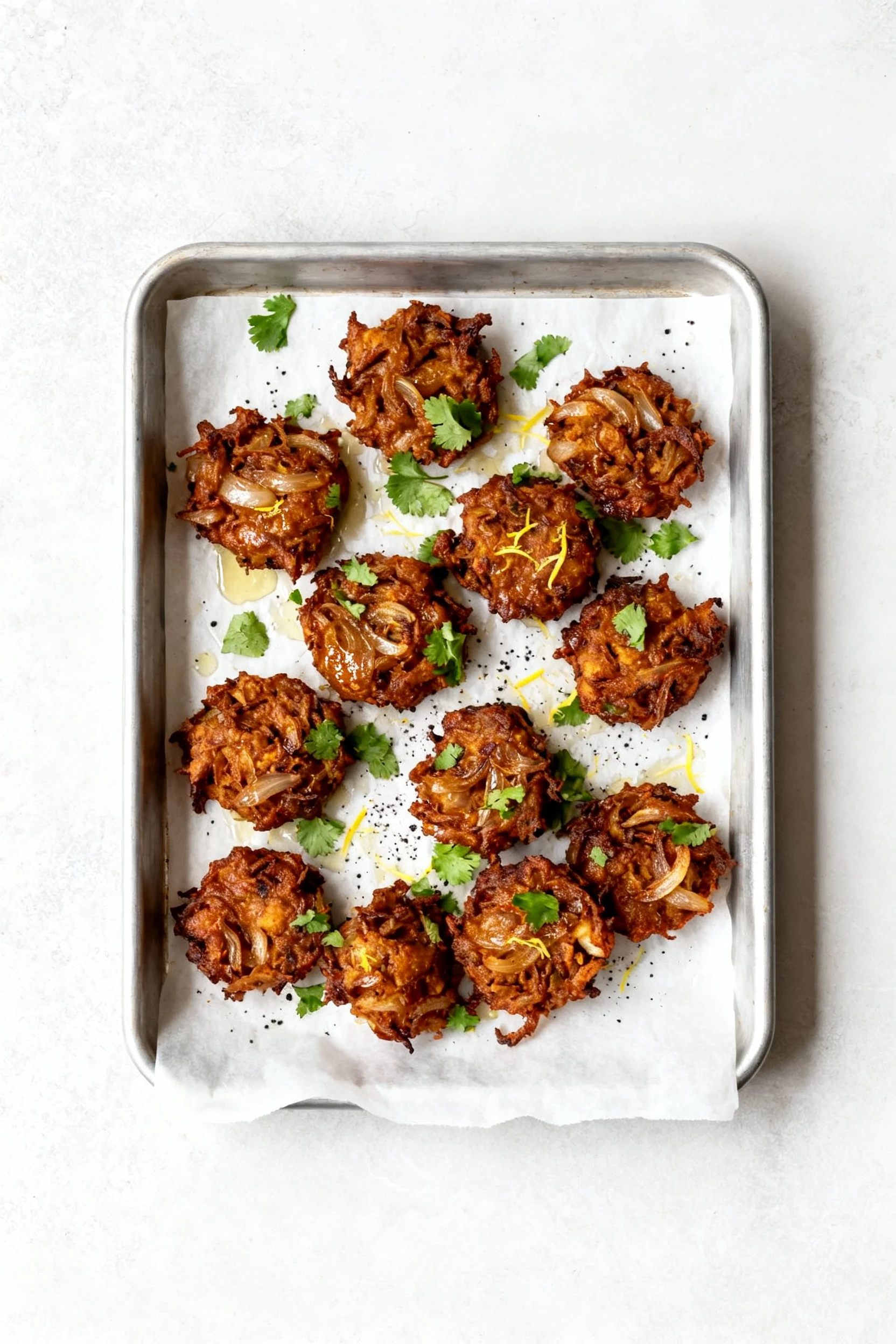Food photography, Overhead top view of air-fried onion bhaji on a parchment-lined tray, evenly browned and crisp with a 