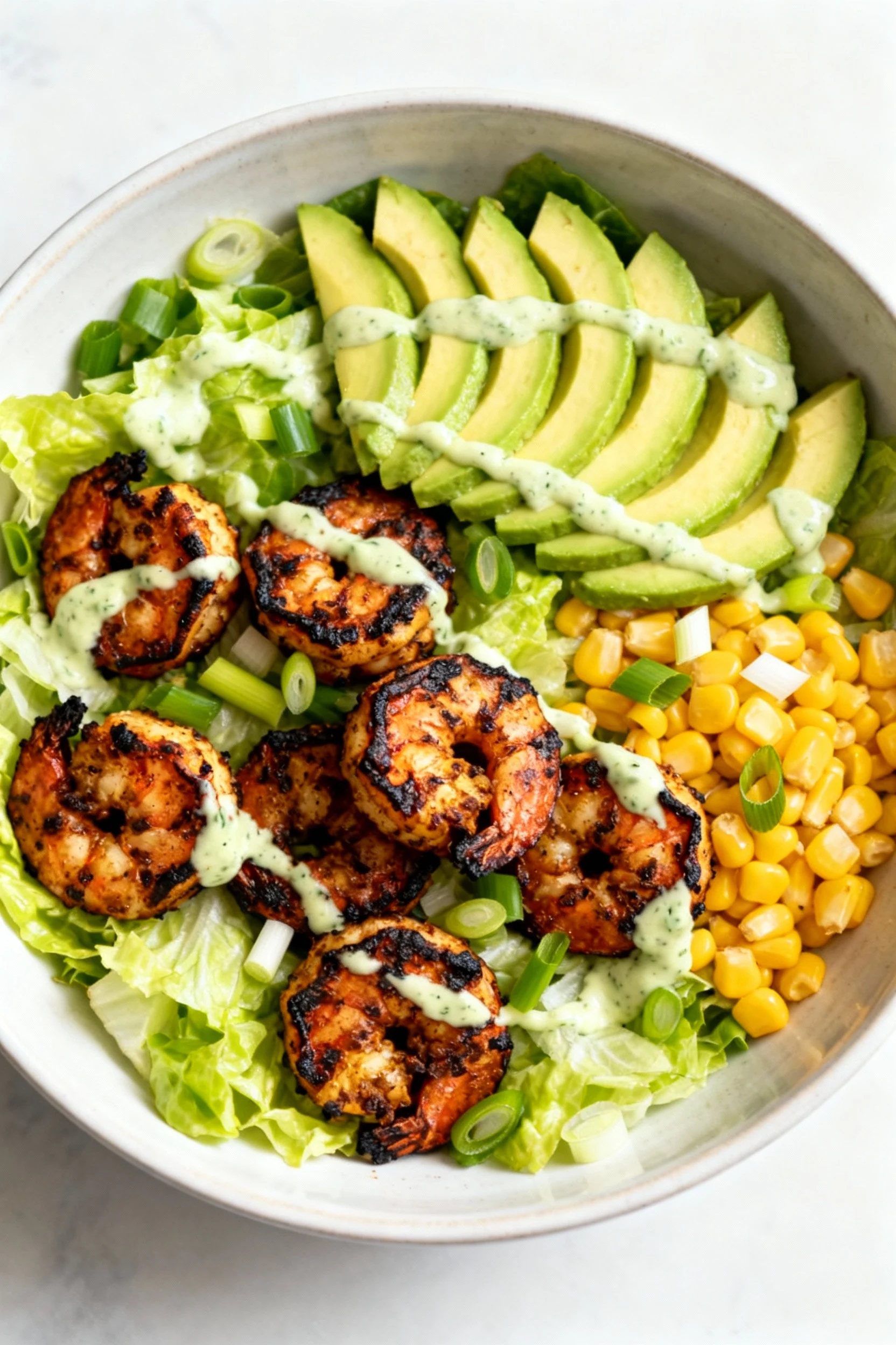 4. Tasty top view of Cajun Avocado shrimp salad: blackened shrimp with charred edges over crisp romaine, sweet corn kern