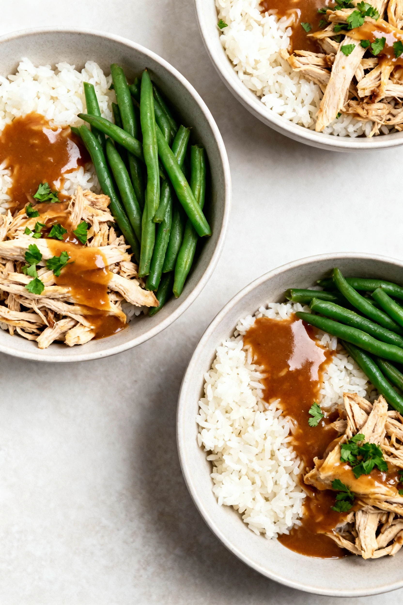 Tasty top view of meal-prep bowls: shredded slow-cooker chicken over fluffy jasmine rice with steamed green beans, gener