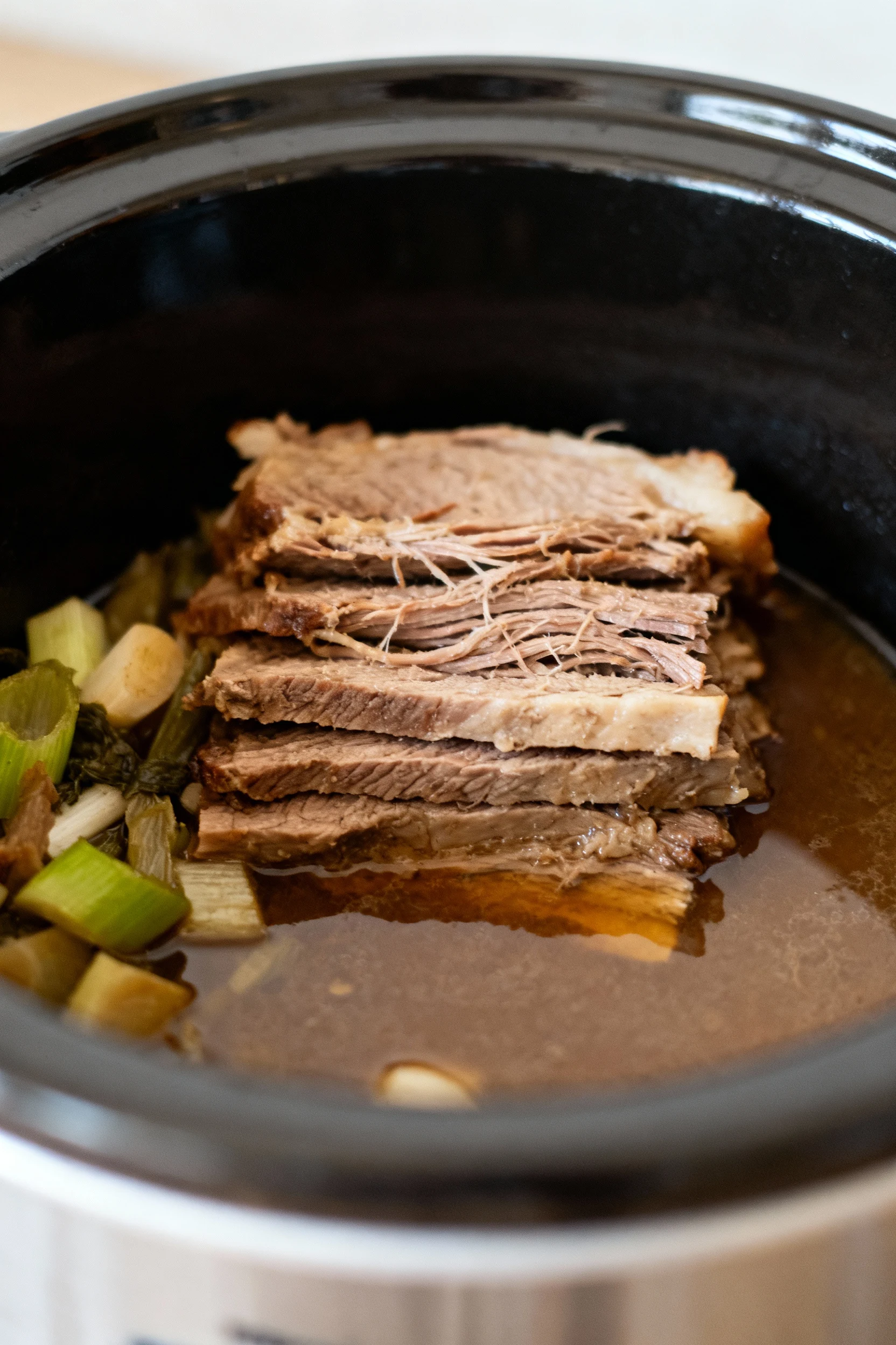 Step-by-step cooking shot showing the layered cooked meat and vegetables inside the slow cooker just after long simmerin