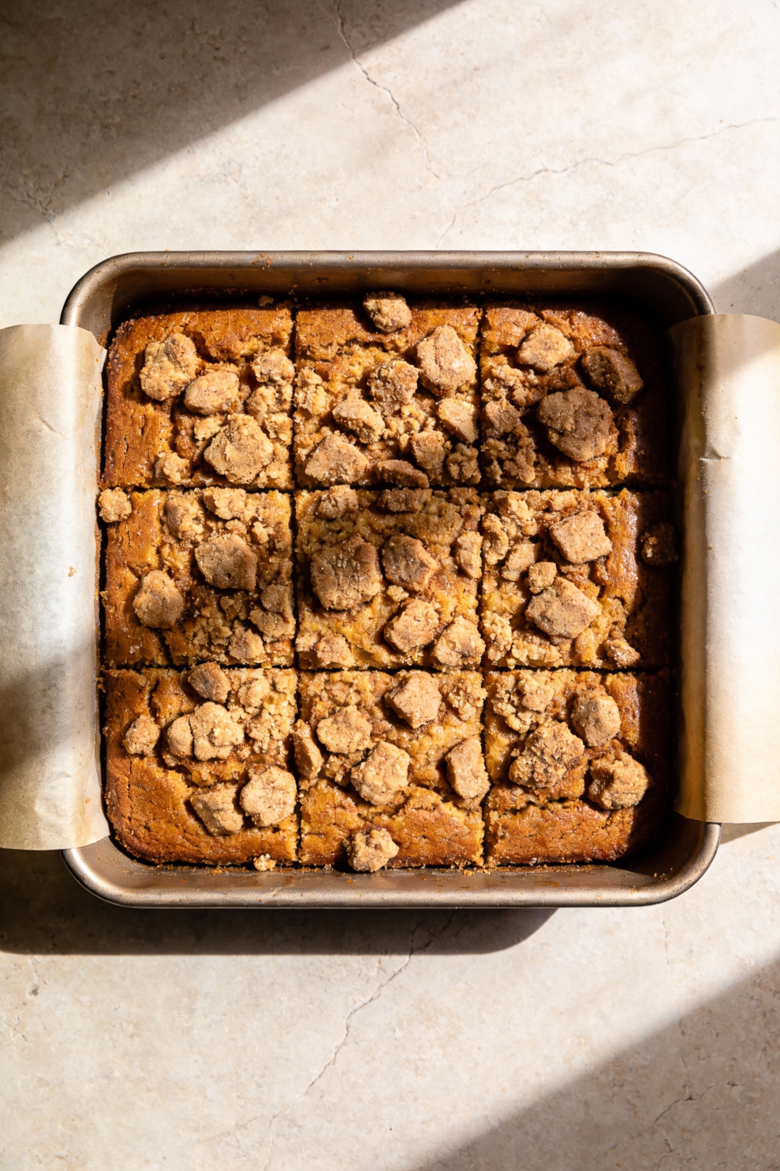 1. Overhead shot of a 9-inch square cinnamon-streusel coffee cake in the pan, thick golden-brown crumb visible through c