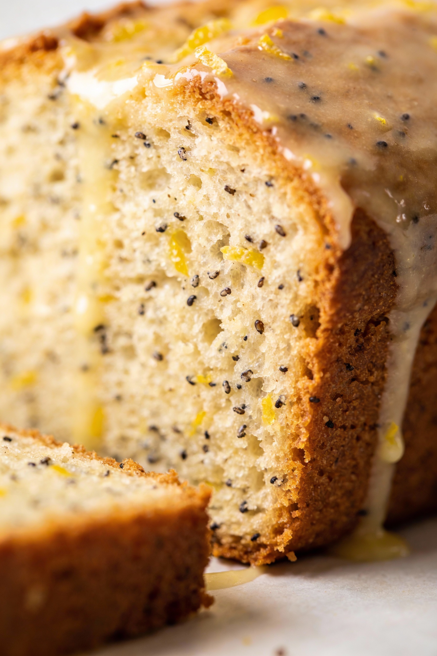 Close-up detail: Lemon poppy seed loaf slice showing ultra-tender, yogurt-moist crumb with poppy seeds and flecks of zes