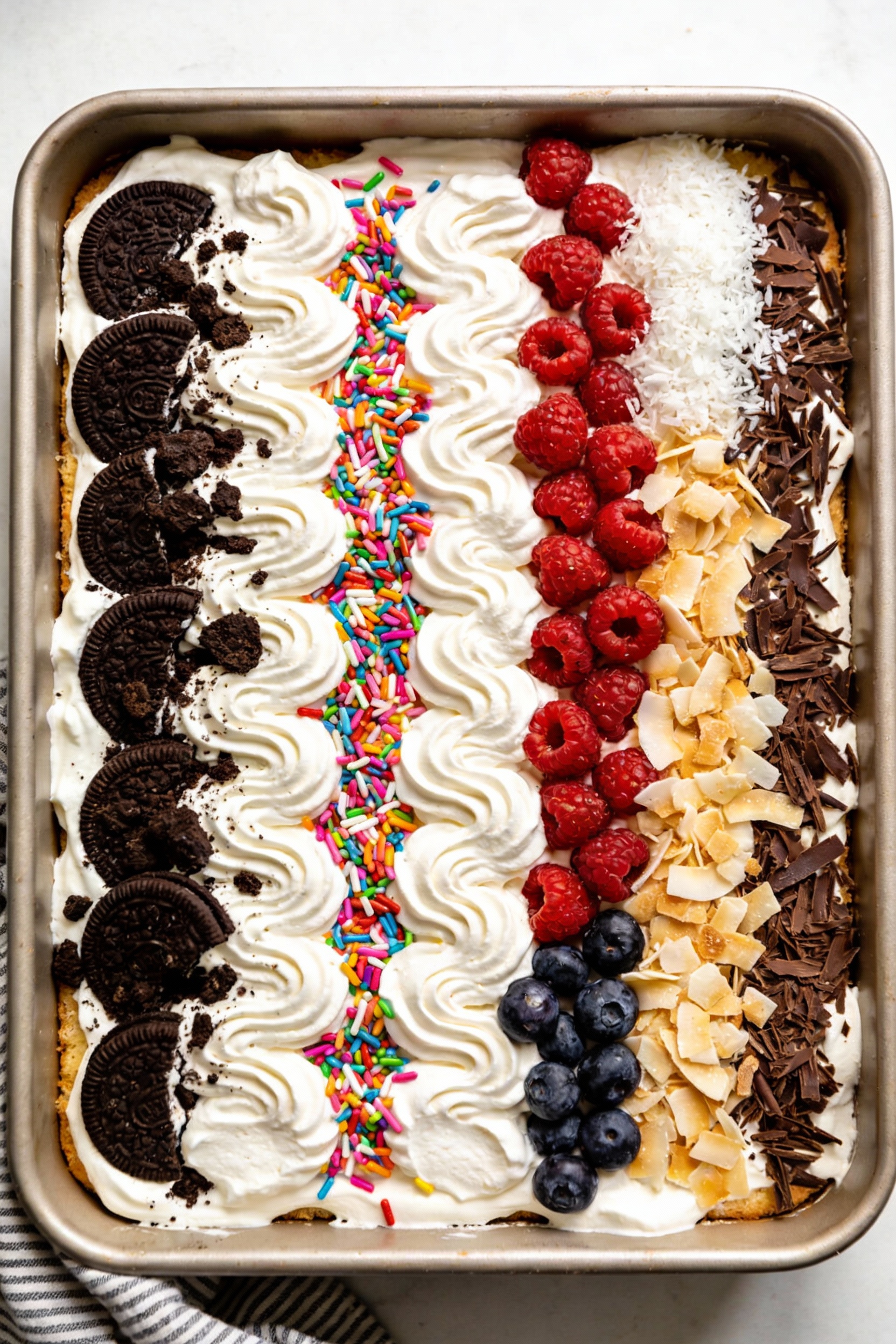 3. Overhead top-down shot of the finished vanilla-and-cream poke cake in the pan, fluffy stabilized whipped topping spre