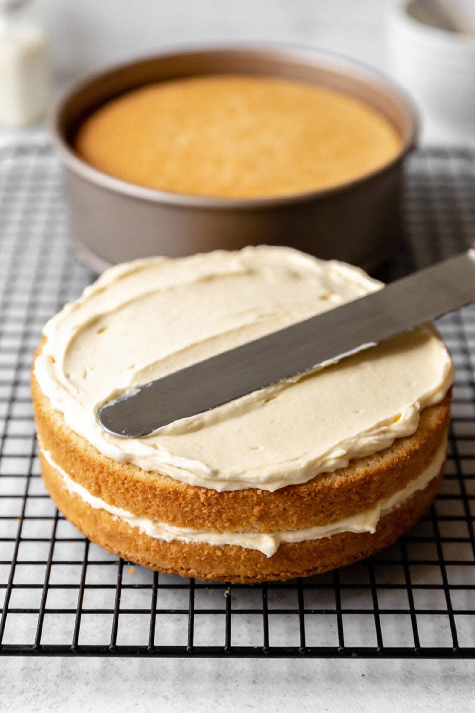 Cooking process: freshly baked vanilla birthday cake layer on a cooling rack, smooth golden top just turned out of the p