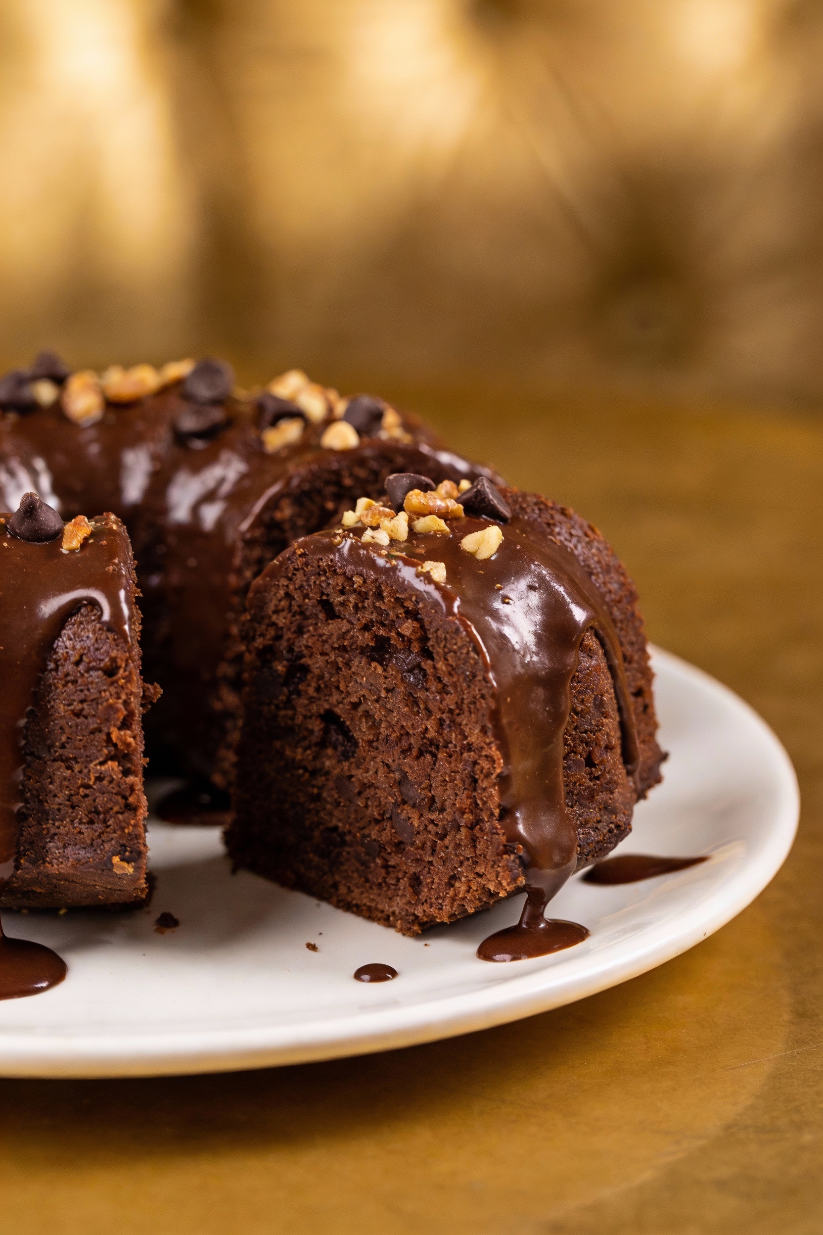 Final dish presentation: a single plated slice of chocolate fudge ring Bundt cake with shiny chocolate ganache cascading