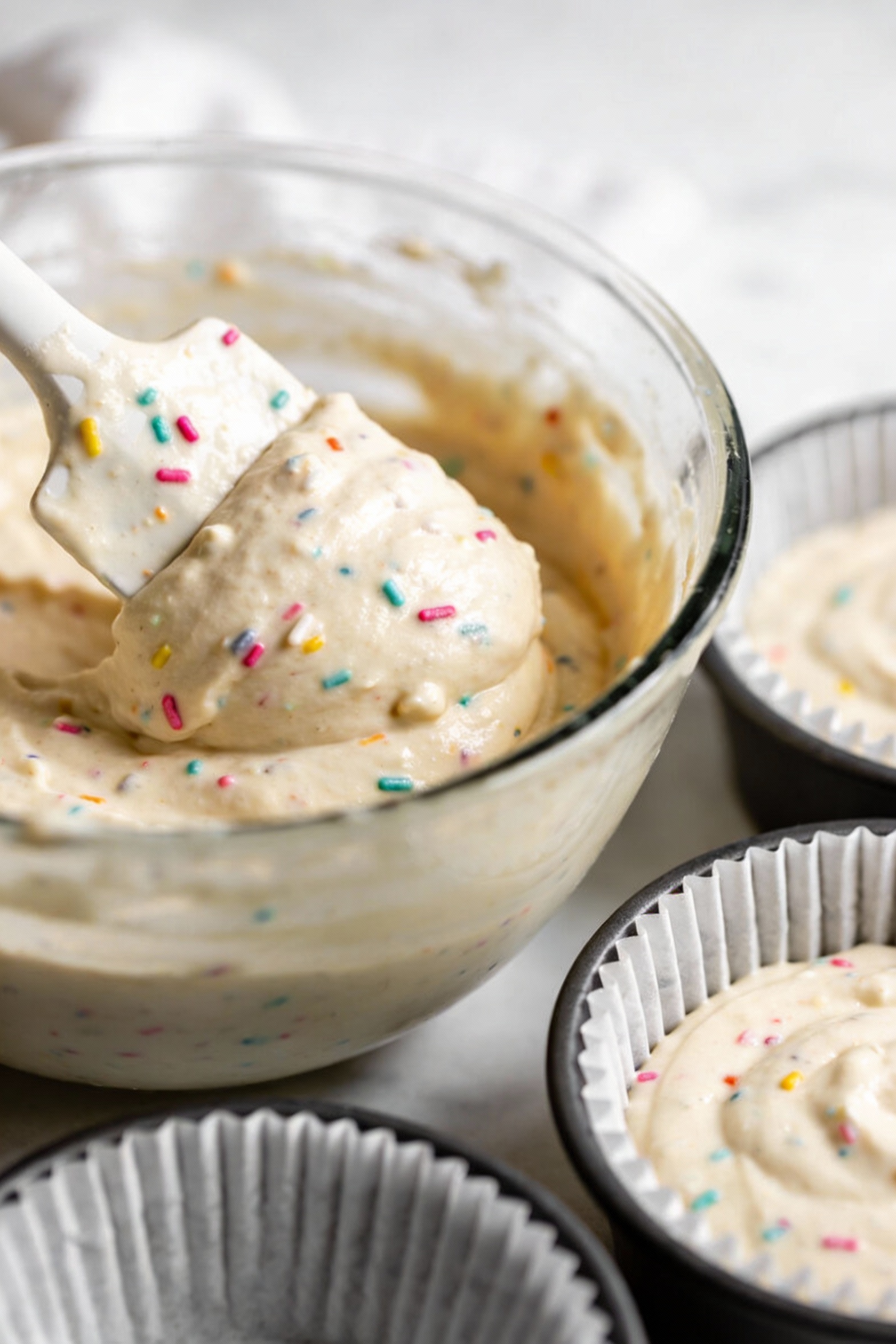 4. Cooking process: vegan cake batter being gently folded in a mixing bowl with a spatula (minimal mixing, small lumps v